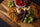 Wooden board with meat sticks, assorted cheeses, crackers, grapes, and cherry tomatoes.