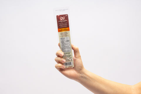 Hand holding a pack of meat sticks. 