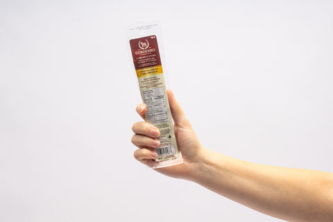 Hand holding a pack of meat sticks. 